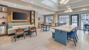 Een moderne hotellobby met een zithoek, een bar en grote ramen met uitzicht over de stad.