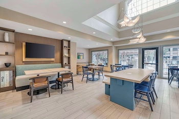 A reception area with a wooden reception desk, a flat-screen TV, and a wall with various posters. at Sonesta ES Suites Torrance Redondo Beach
