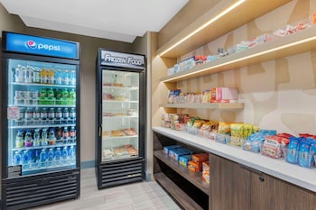 A modern kitchen with white and blue cabinets, a black refrigerator, a microwave, and a white countertop. at Sonesta ES Suites Torrance Redondo Beach