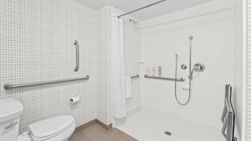 A modern bathroom with a toilet, a shower with a glass door, and a grab bar for safety.