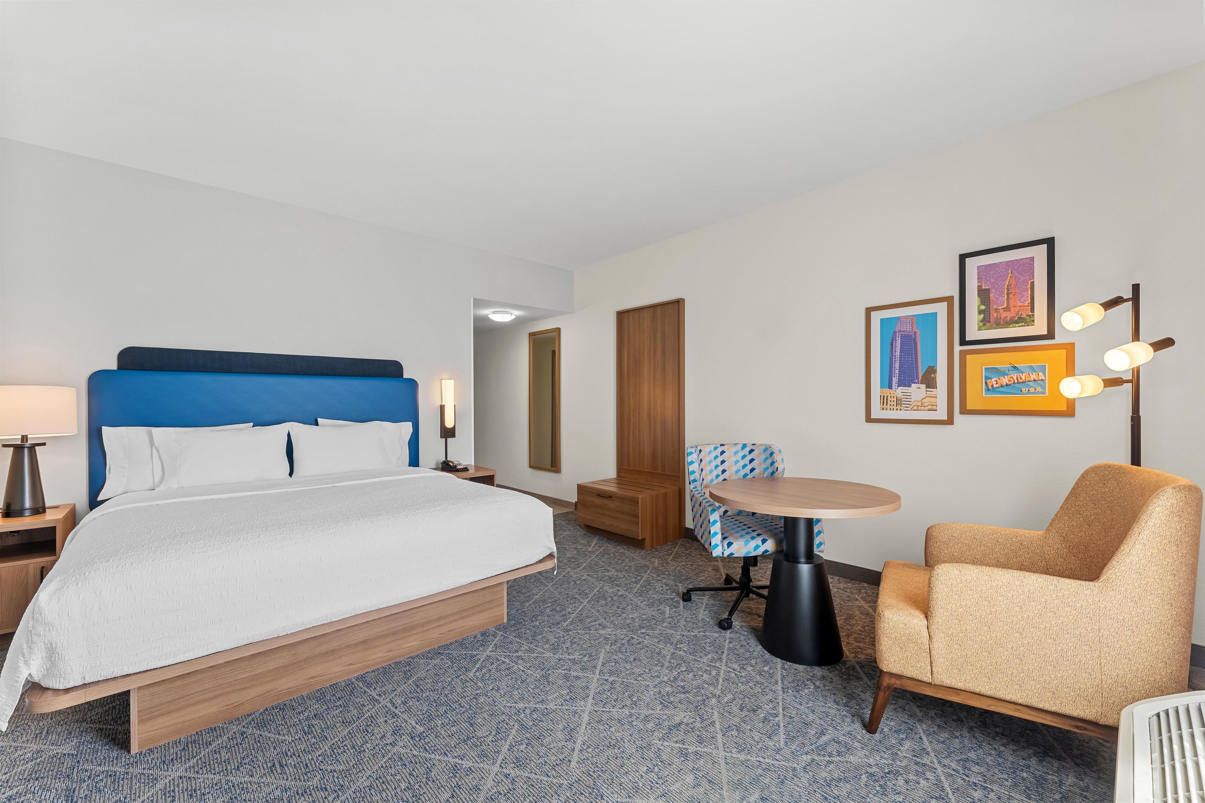 Una habitación de hotel con una cama, un escritorio, una silla y una mesita.