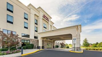 A Hampton Inn & Suites hotel with a modern facade, a covered entrance, and a clear sky.