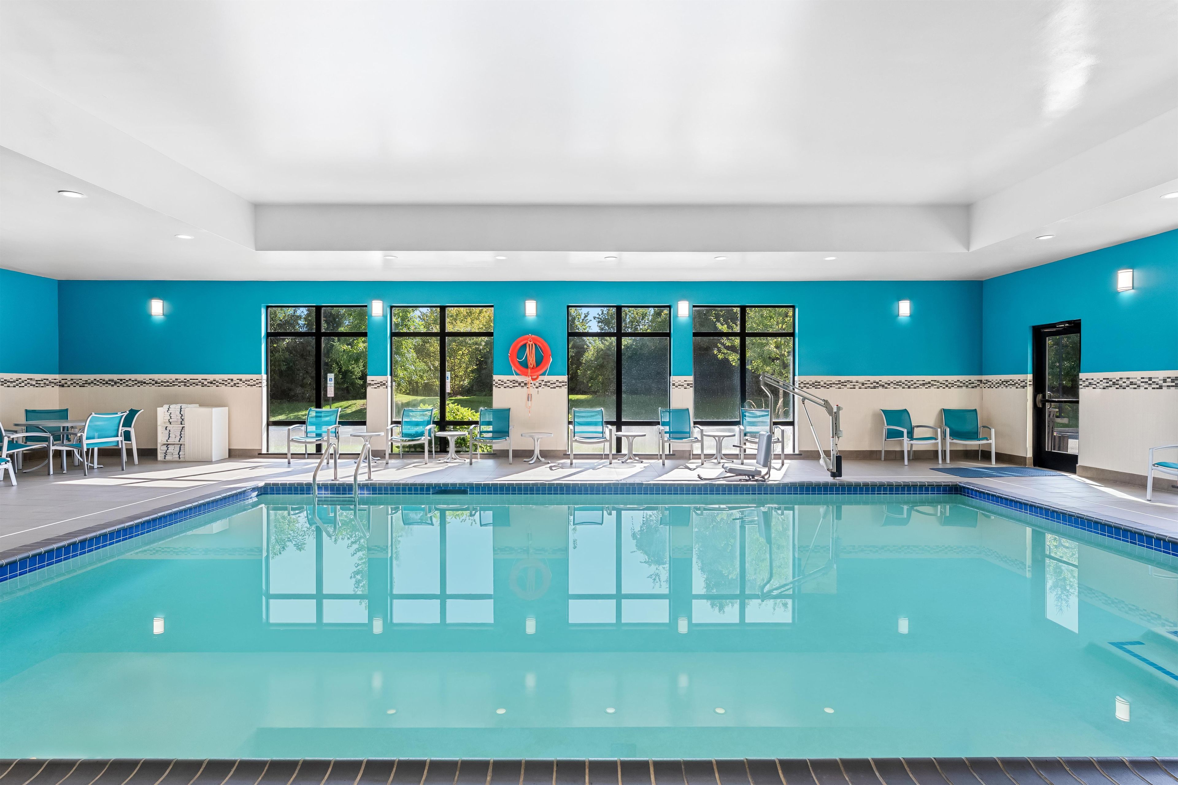 A swimming pool with clear blue water, surrounded by lounge chairs and tables.