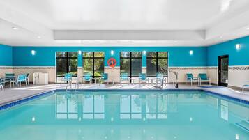 A swimming pool with clear blue water, surrounded by lounge chairs and tables.