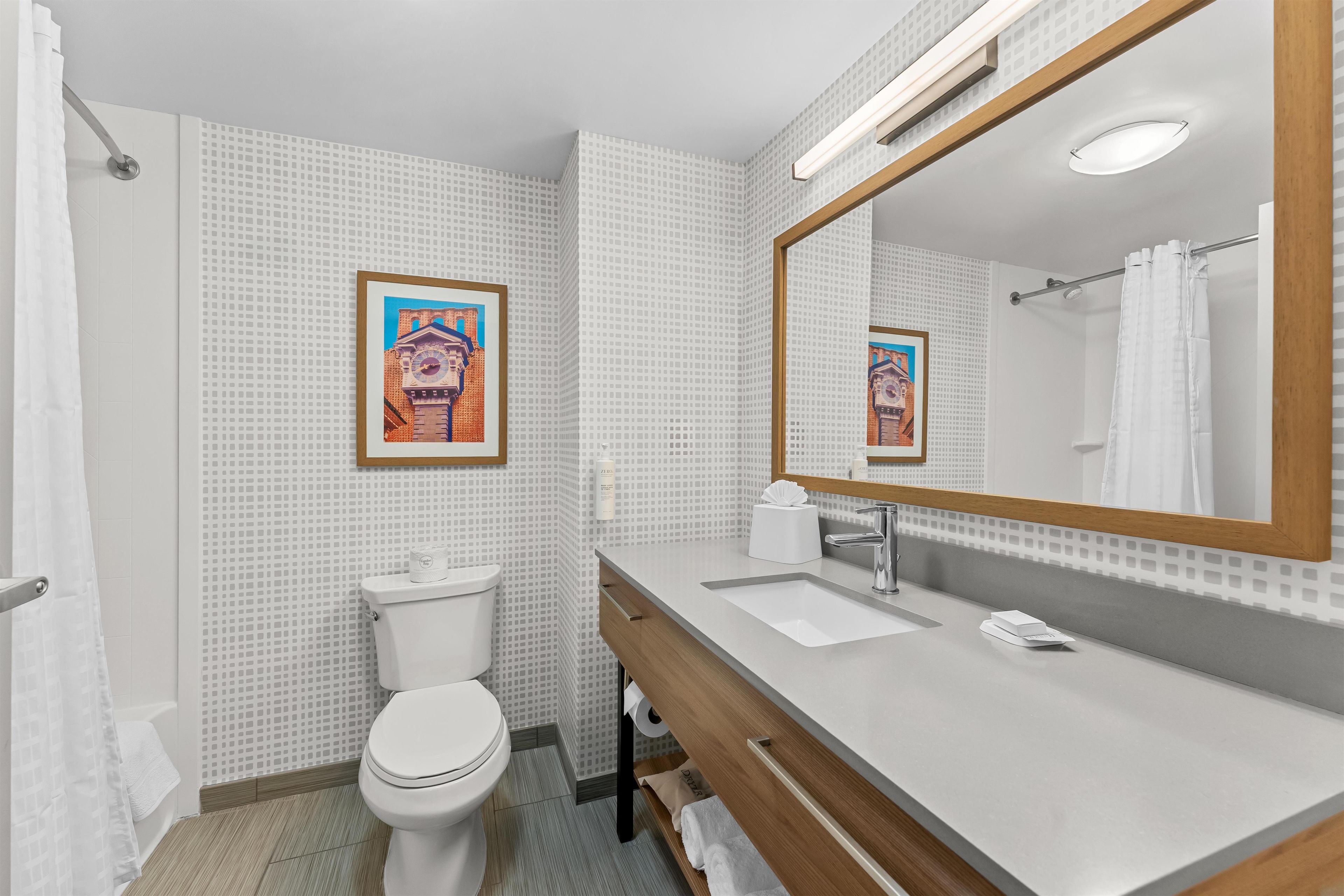 A modern bathroom with a toilet, sink, and mirror.