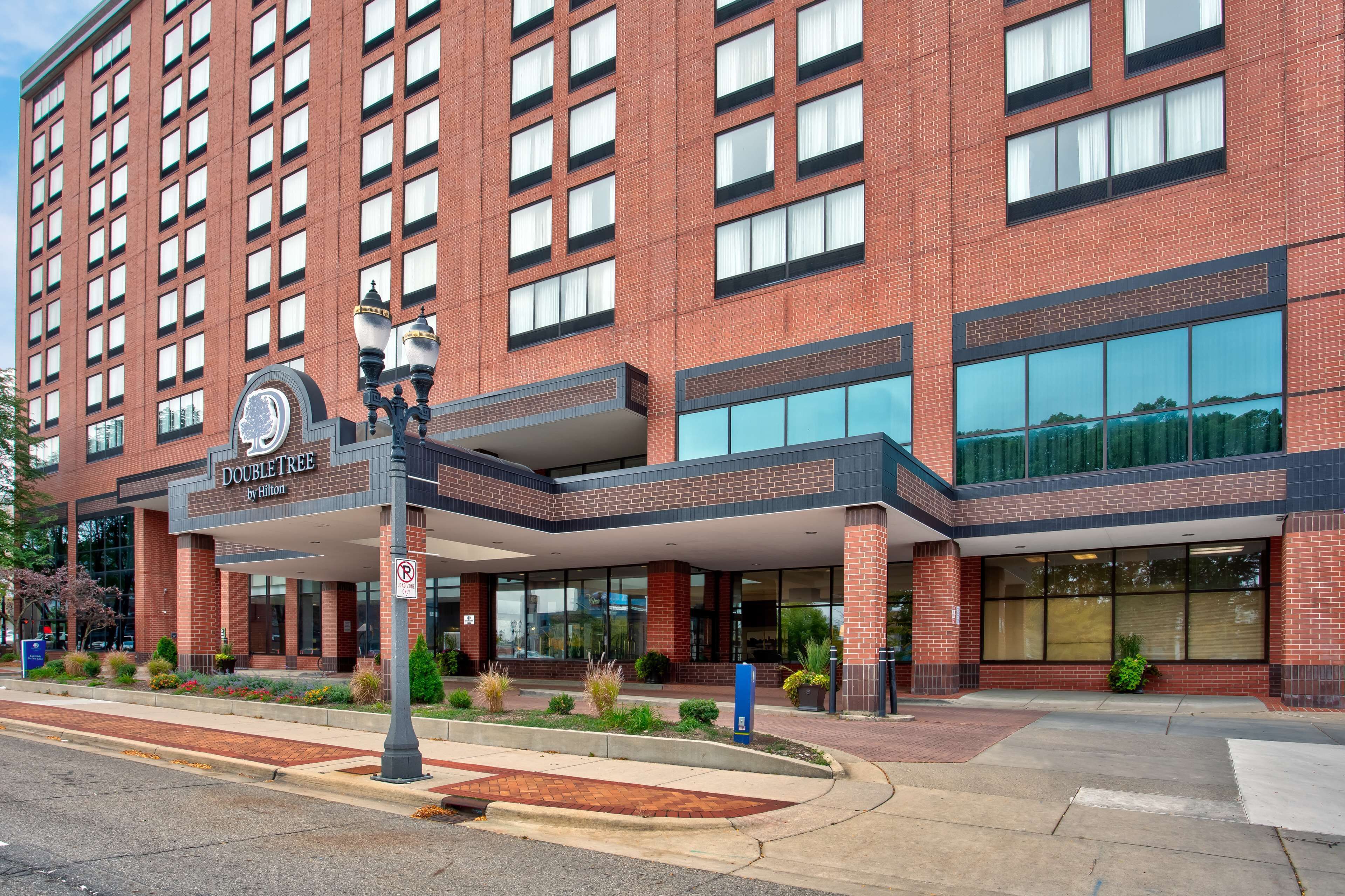 A DoubleTree by Hilton hotel with a brick facade, large windows, and a covered entrance area.