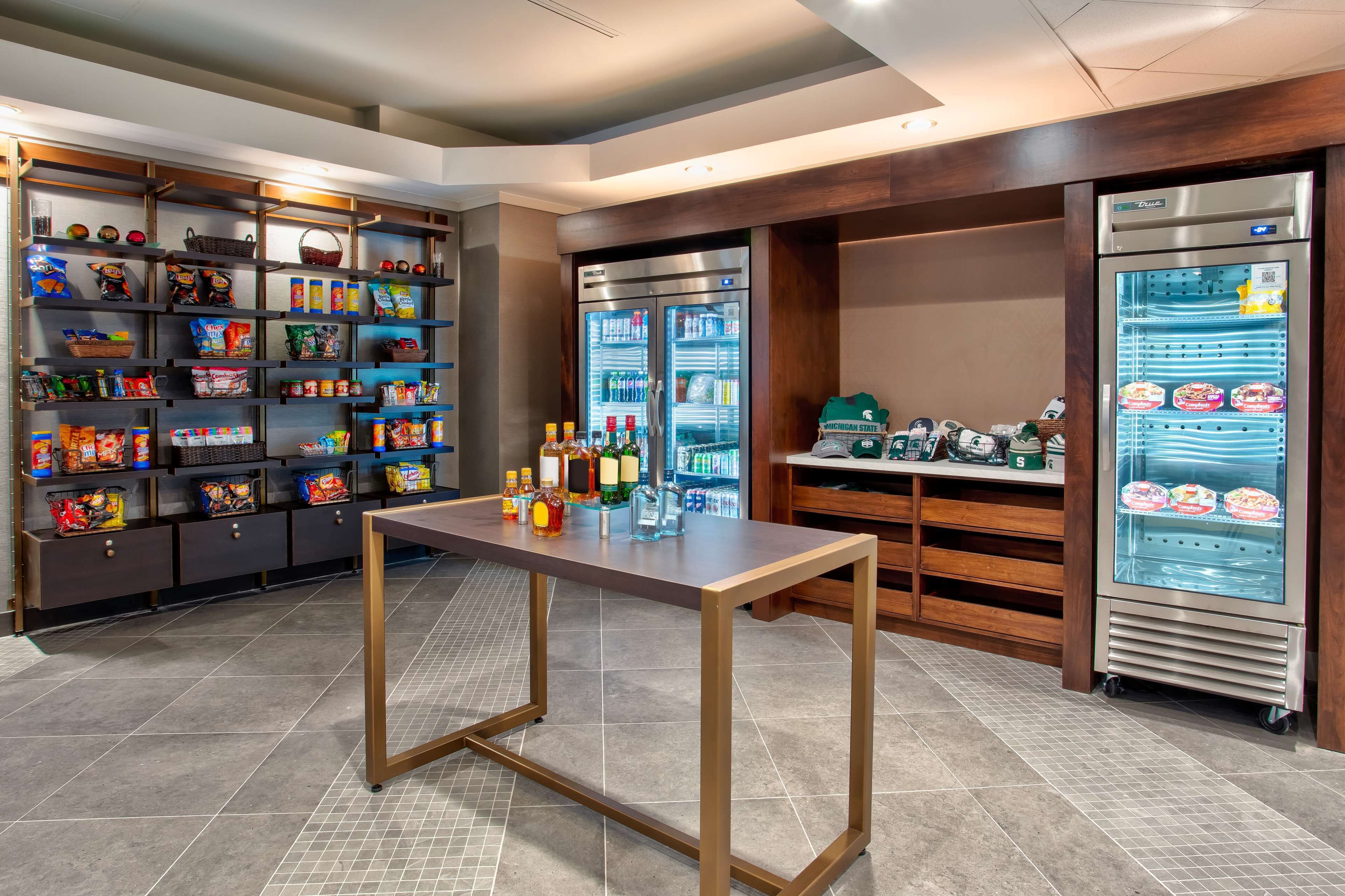 Una zona d'autoservei per a aperitius i begudes, amb prestatges plens de diferents mossegàvers i un refrigerador amb begutgeries.