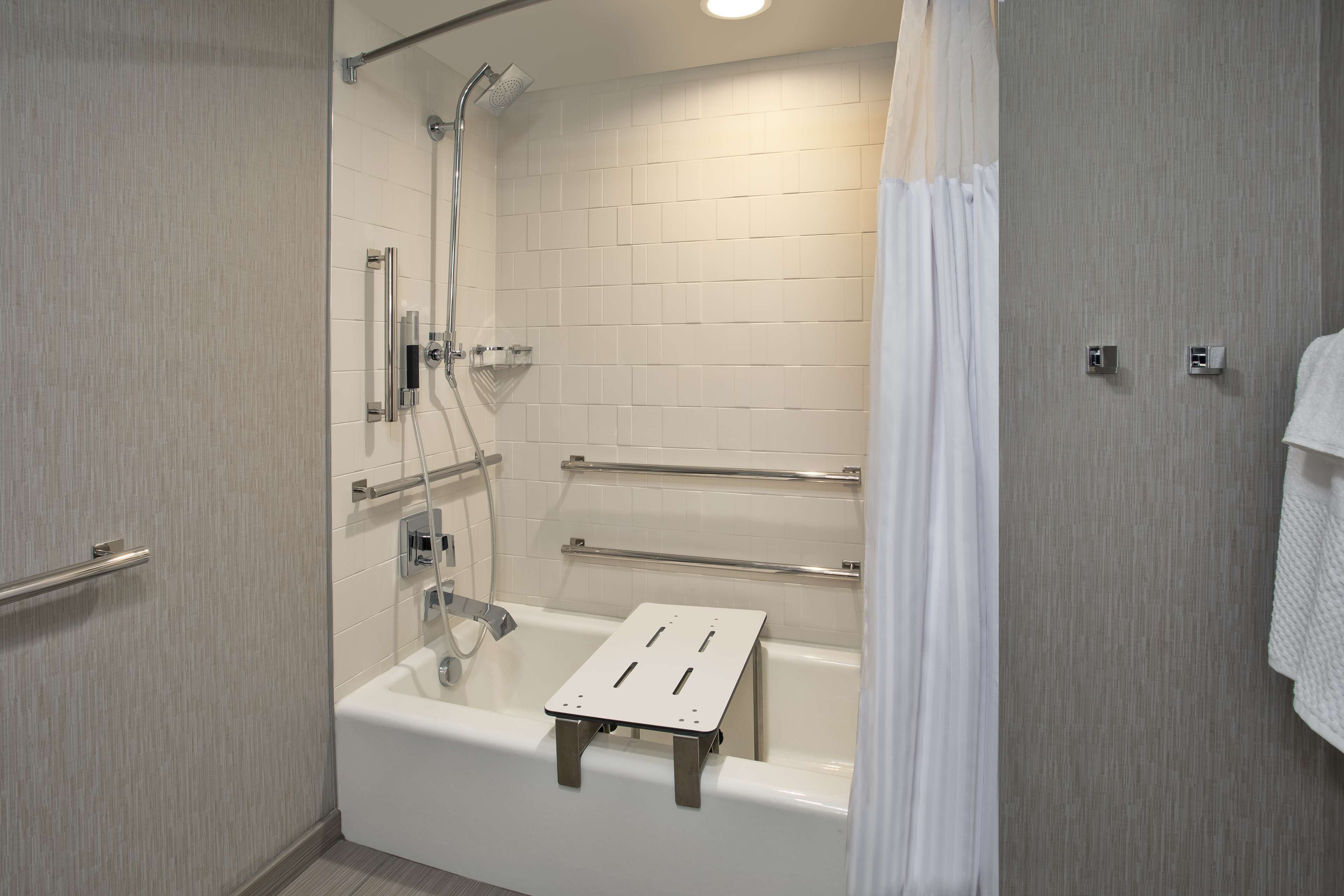 A modern bathroom with a walk-in shower, grab bars, and a white bathtub.