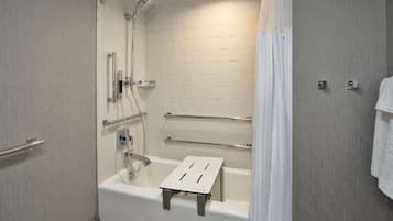 A modern bathroom with a walk-in shower, grab bars, and a white bathtub.