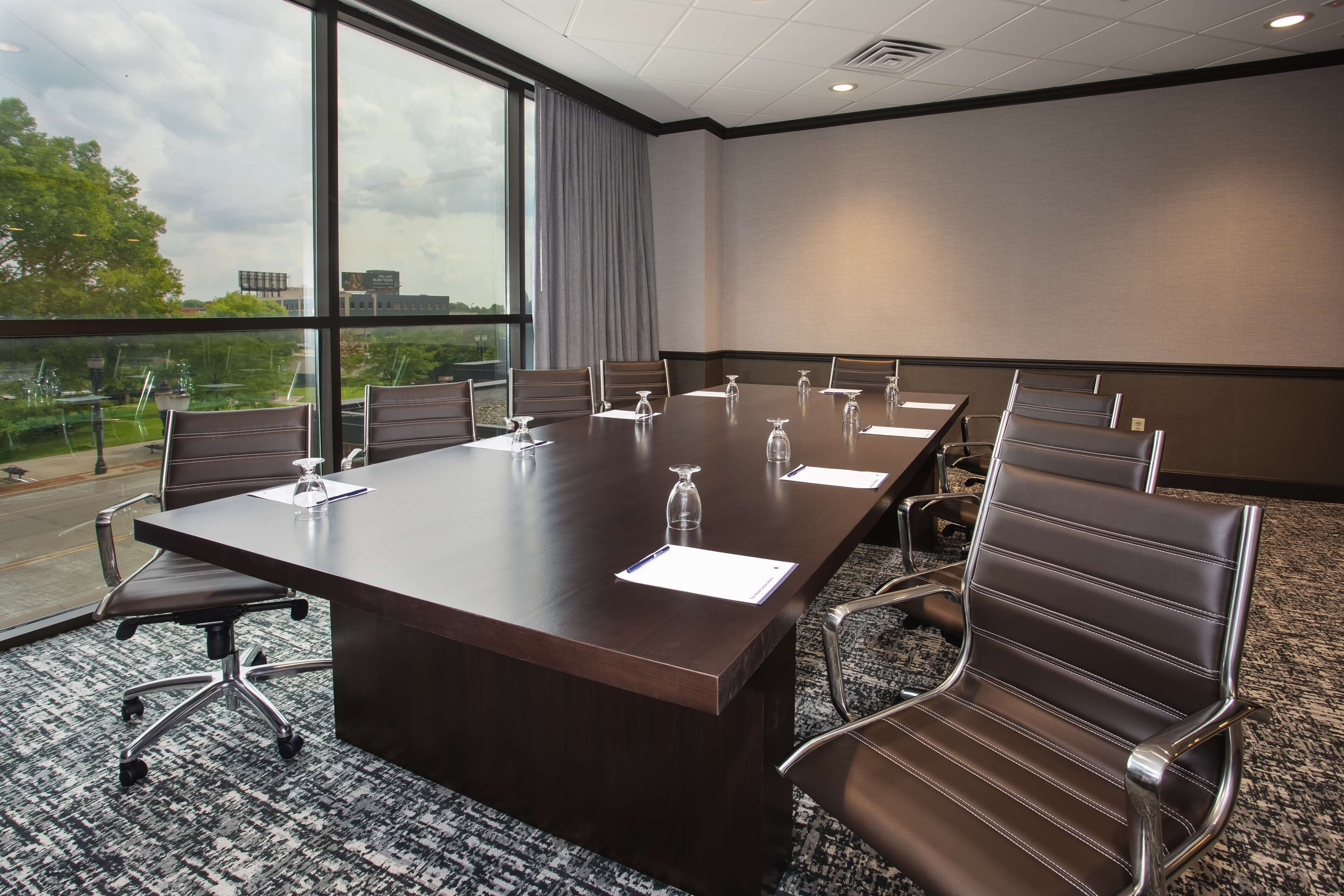A conference room with a large table, chairs, and a view of the outdoors.