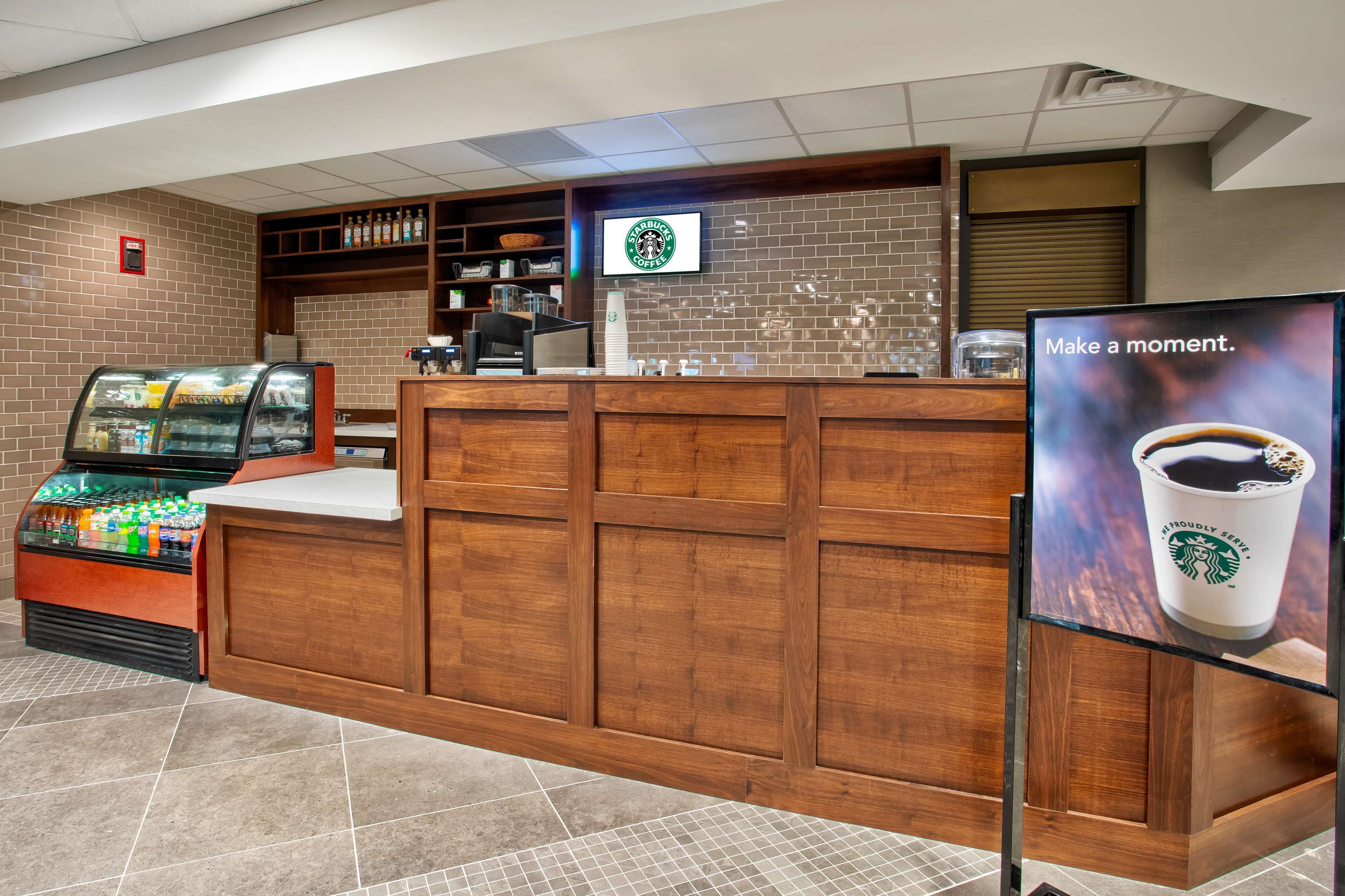 A Starbucks coffee shop interior with a wooden counter, a beverage dispenser, and a menu display.