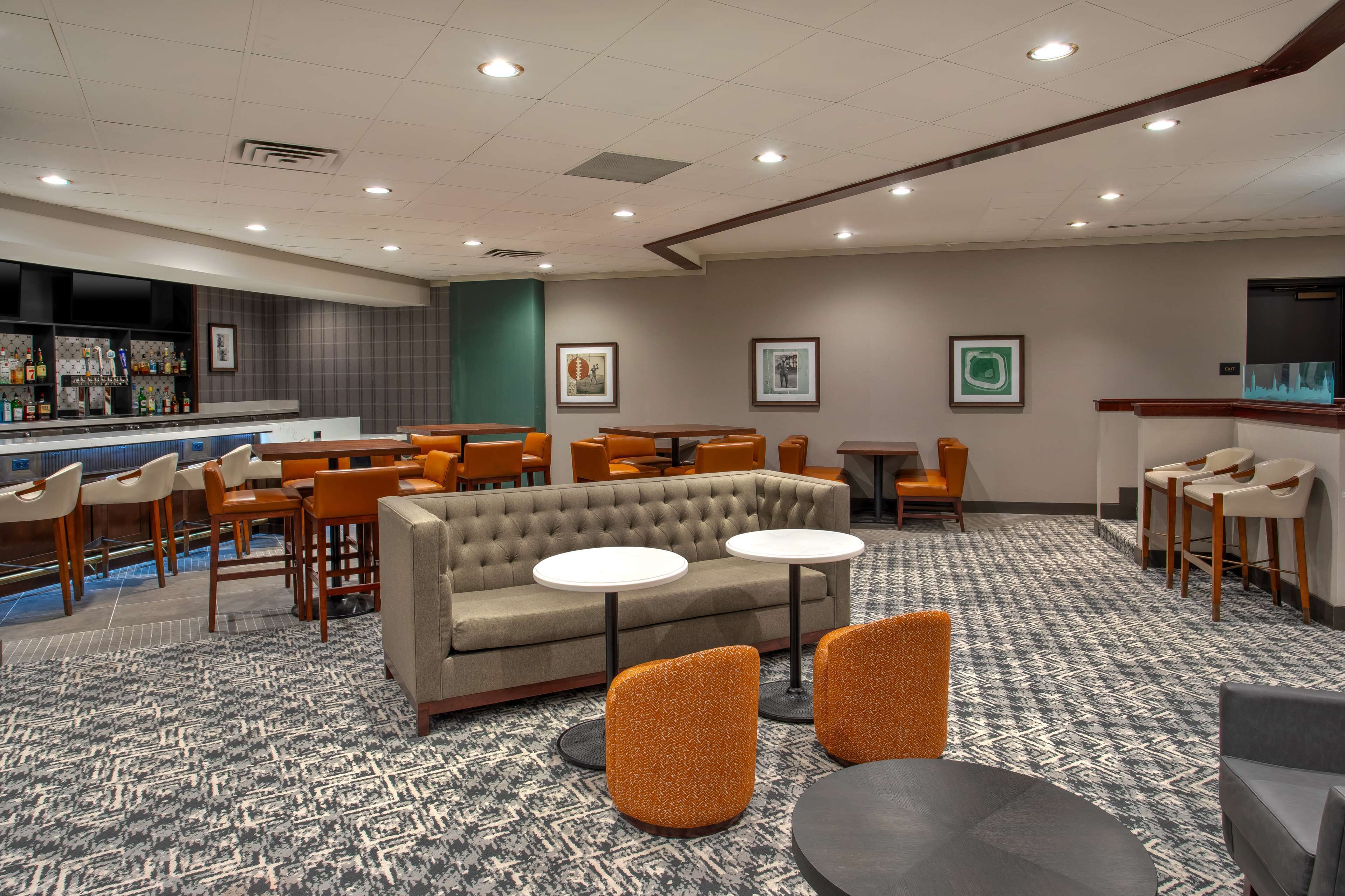 A hotel lobby with a bar area, seating arrangements, and a patterned carpet.