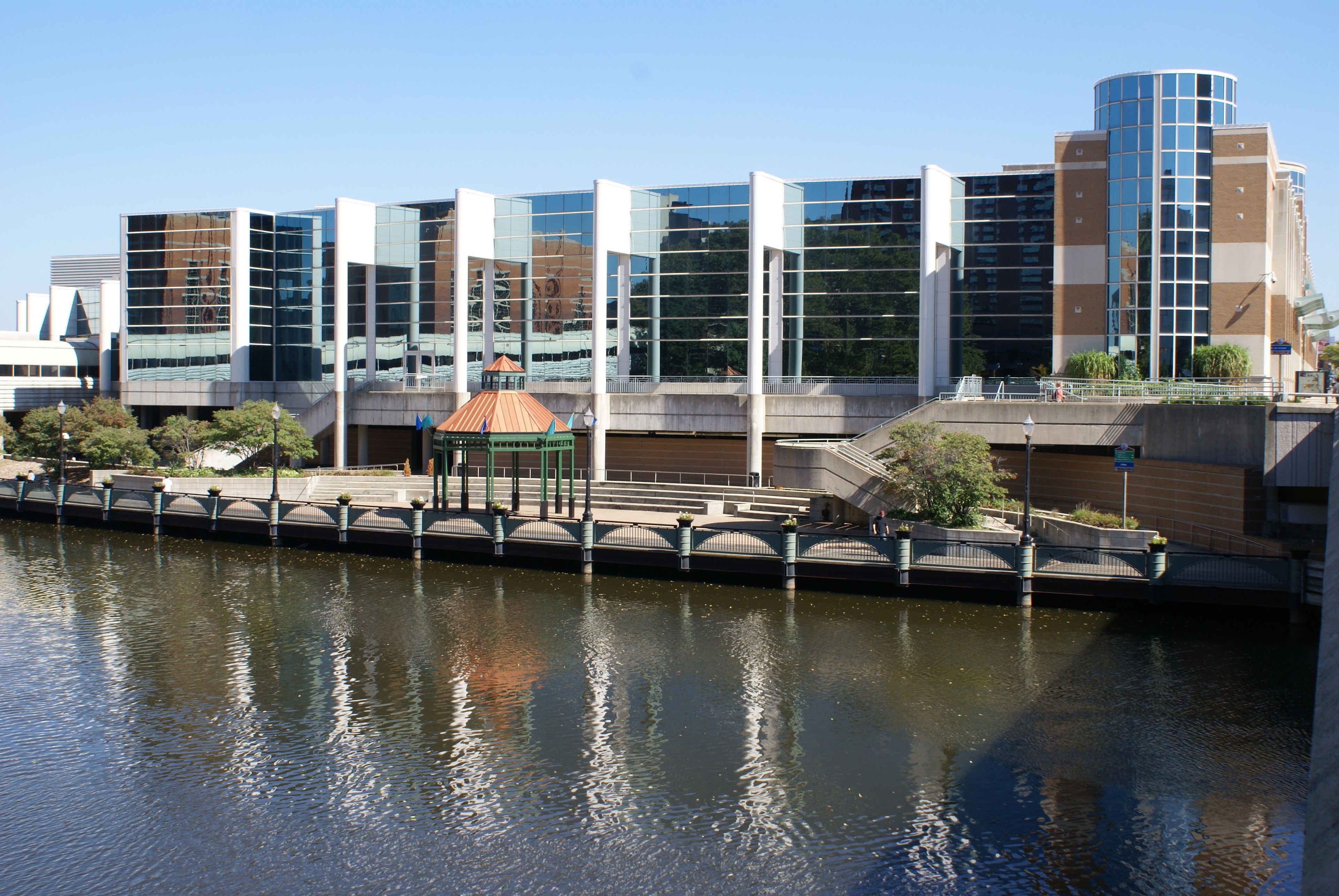 A modern building with reflective glass windows, a bridge, and a canal.
