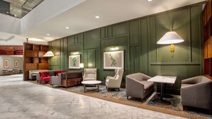 A lobby with a marble floor, green paneled walls, and a seating area with armchairs and a sofa. - DoubleTree by Hilton Lansing (Lansing)