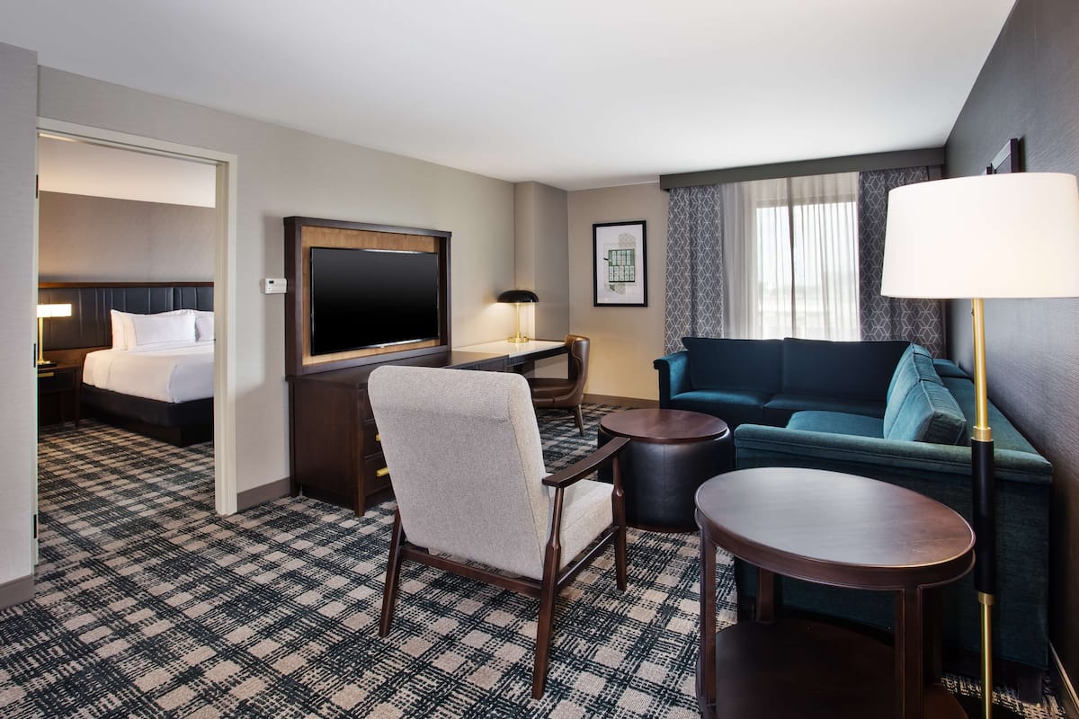 Una habitación de hotel con cama, sofá, televisión, escritorio y lámpara.