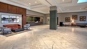 A spacious lobby with a reception desk, seating area, and artwork on the walls. - DoubleTree by Hilton Lansing (Lansing)
