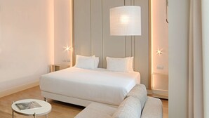 Una habitación de hotel moderna con una cama grande, una mesita redonda pequeña y un sofá.