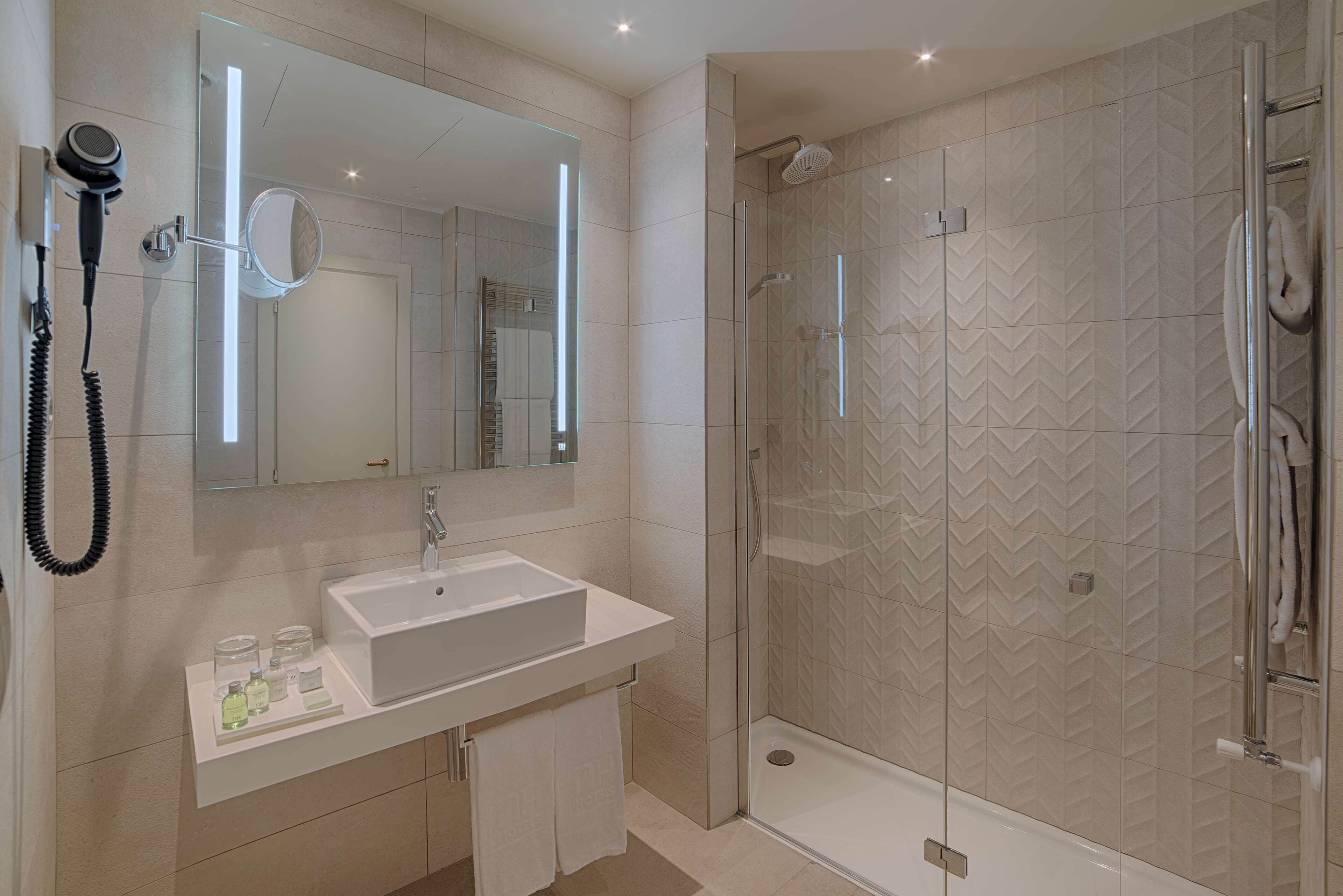 Un baño moderno con un espejo grande, un lavamanos y una zona de ducha.