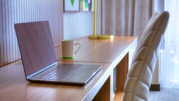 Un ordinateur portable sur un bureau en bois, avec une tasse blanche et une lampe.
