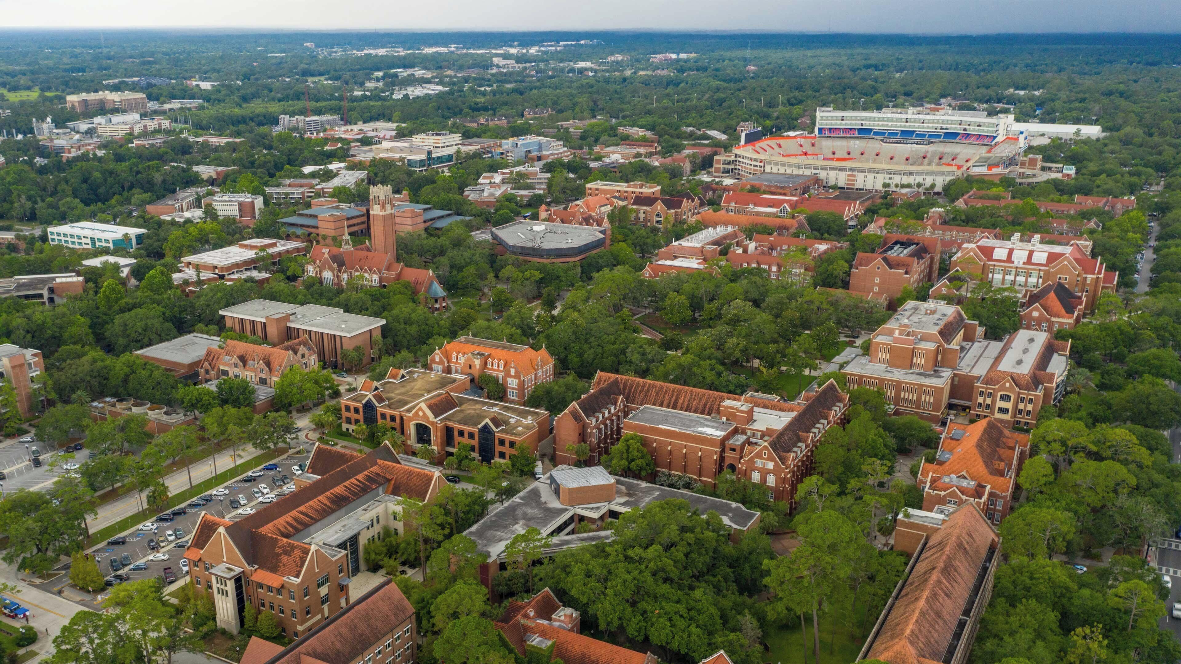 An aerial view of a campus with multiple buildings, including a large stadium.