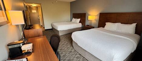 Ein Hotelzimmer mit zwei Betten, einem Schreibtisch mit Telefon und einem Stuhl.