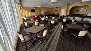 A restaurant with multiple tables and chairs, a bar area, and a television screen on the wall. - Quality Inn & Suites (Sydney)
