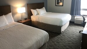 A hotel room with two beds, a nightstand with a lamp, a framed picture on the wall, and an air conditioning unit. - Quality Inn & Suites (Sydney)
