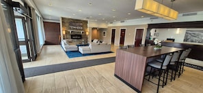 A modern living room with a fireplace, sofas, a coffee table, and a bar area.