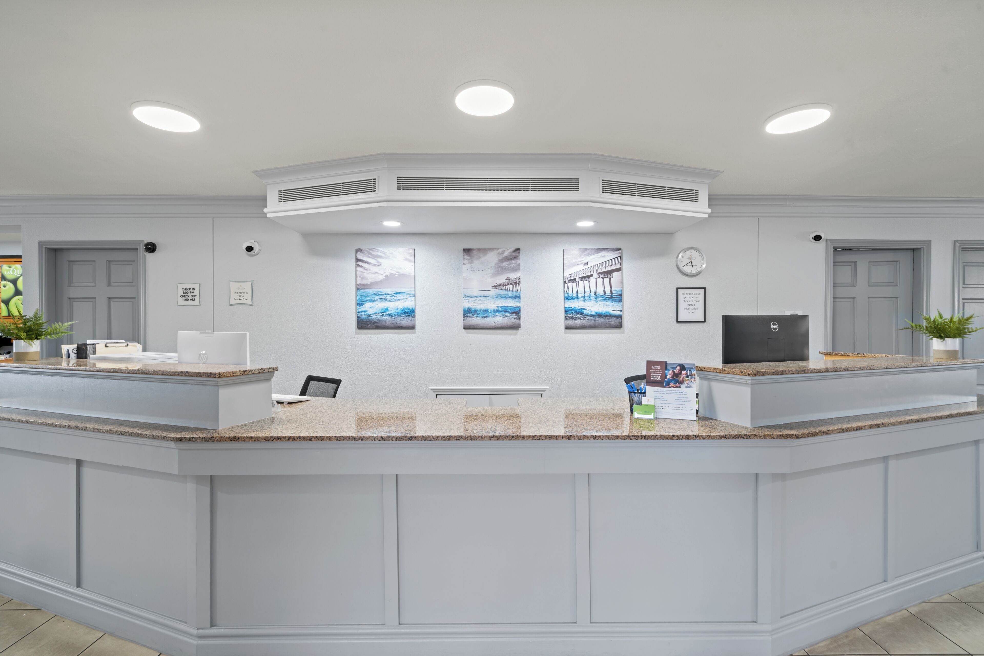A reception area with a curved counter, three framed pictures on the wall, and a clock.