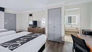Une chambre d’hôtel avec deux lits, une télévision, un bureau, un miroir et une armoire.