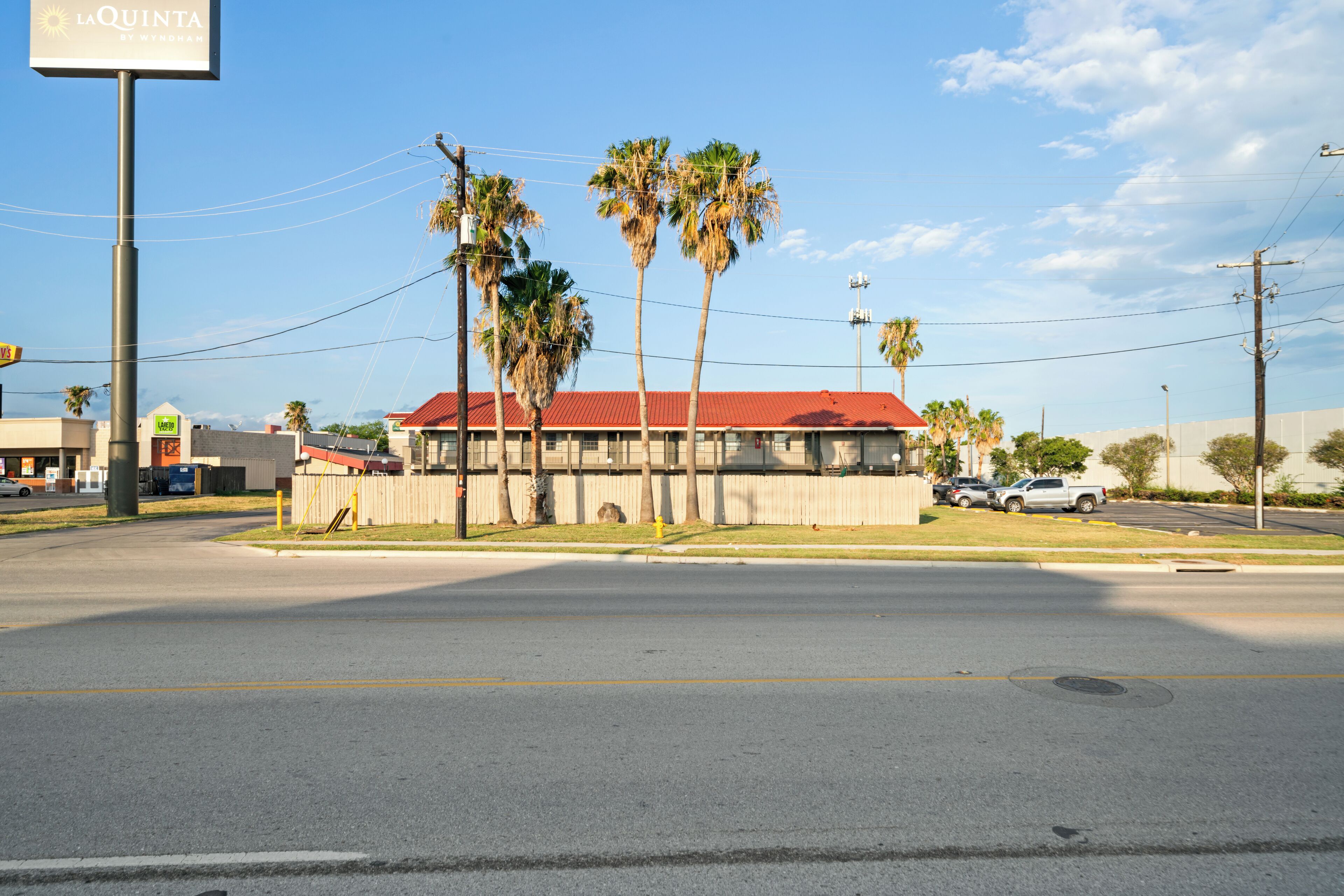 A building with a red roof and palm trees in front.