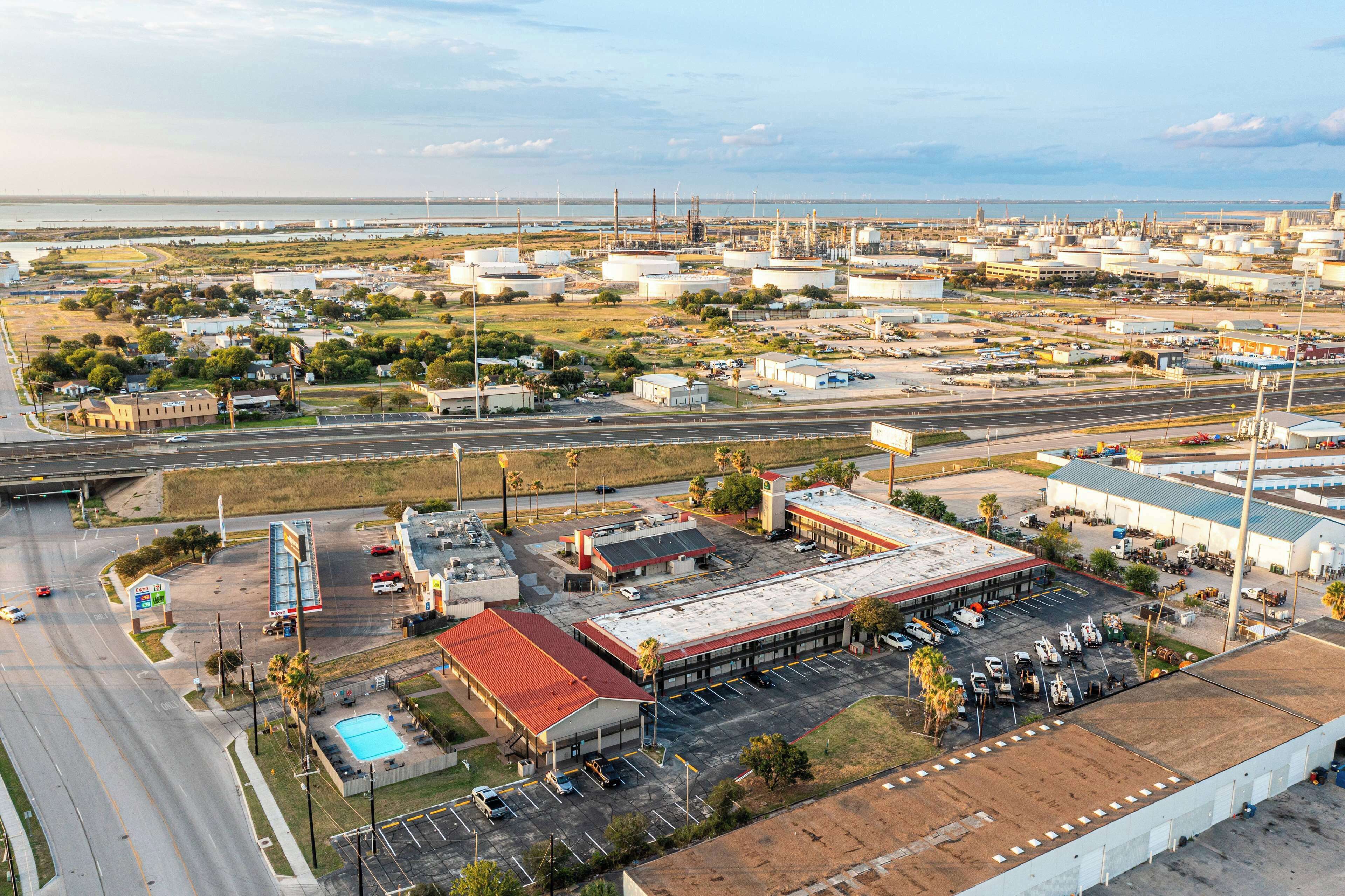 Zona industrial con tanques de almacenamiento grandes, un estacionamiento y una gasolinera.