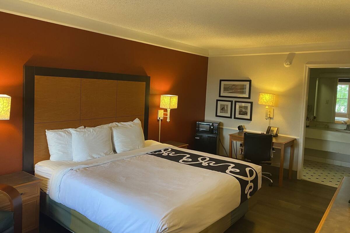 Une chambre d’hôtel comprenant un lit, une table de chevet, une lampe et un bureau avec une chaise.