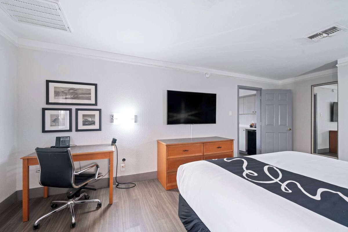 Une chambre d’hôtel comprenant un lit, un bureau avec une chaise, une télévision et une commode.