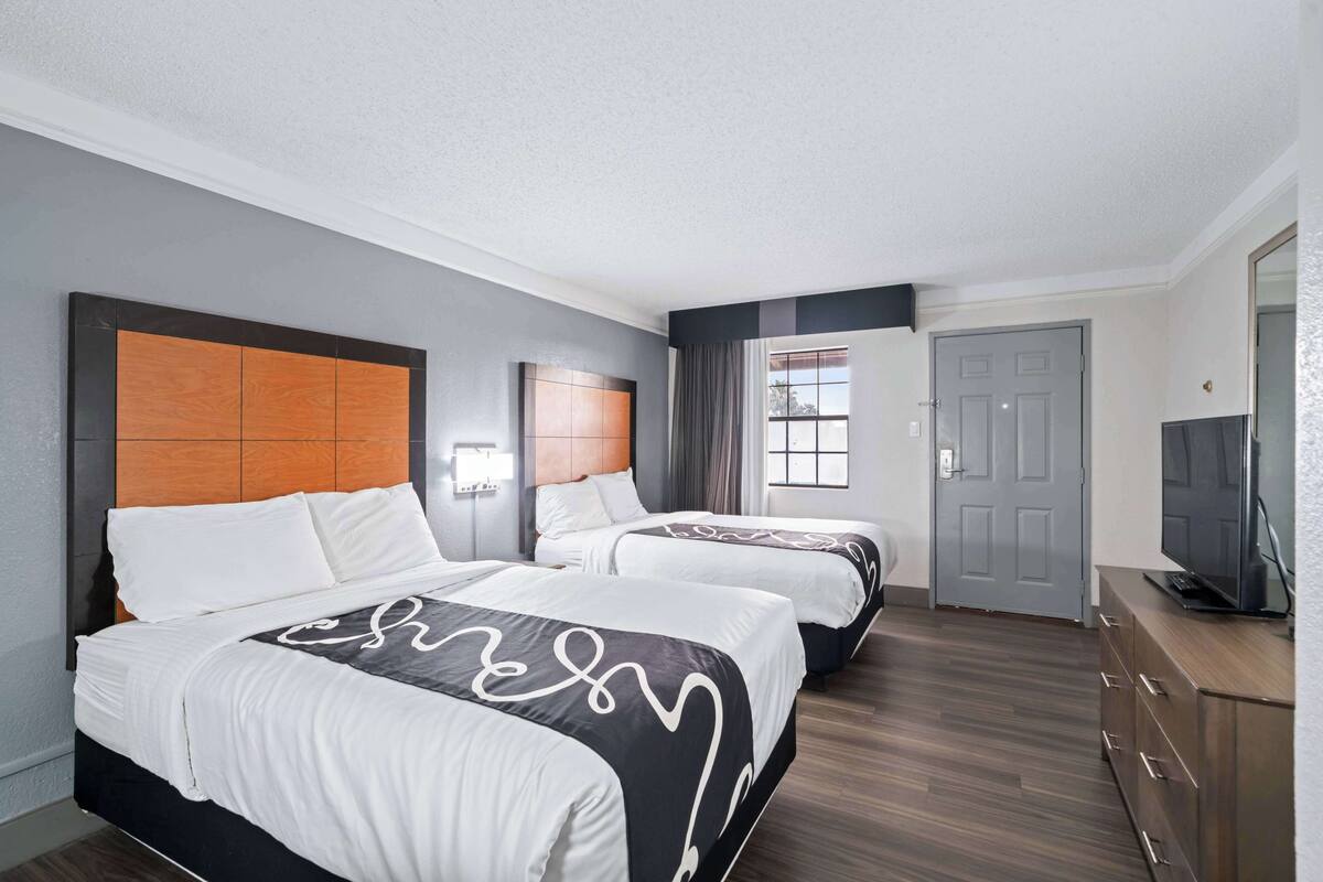 Une chambre d’hôtel avec deux lits, une télévision et une armoire.