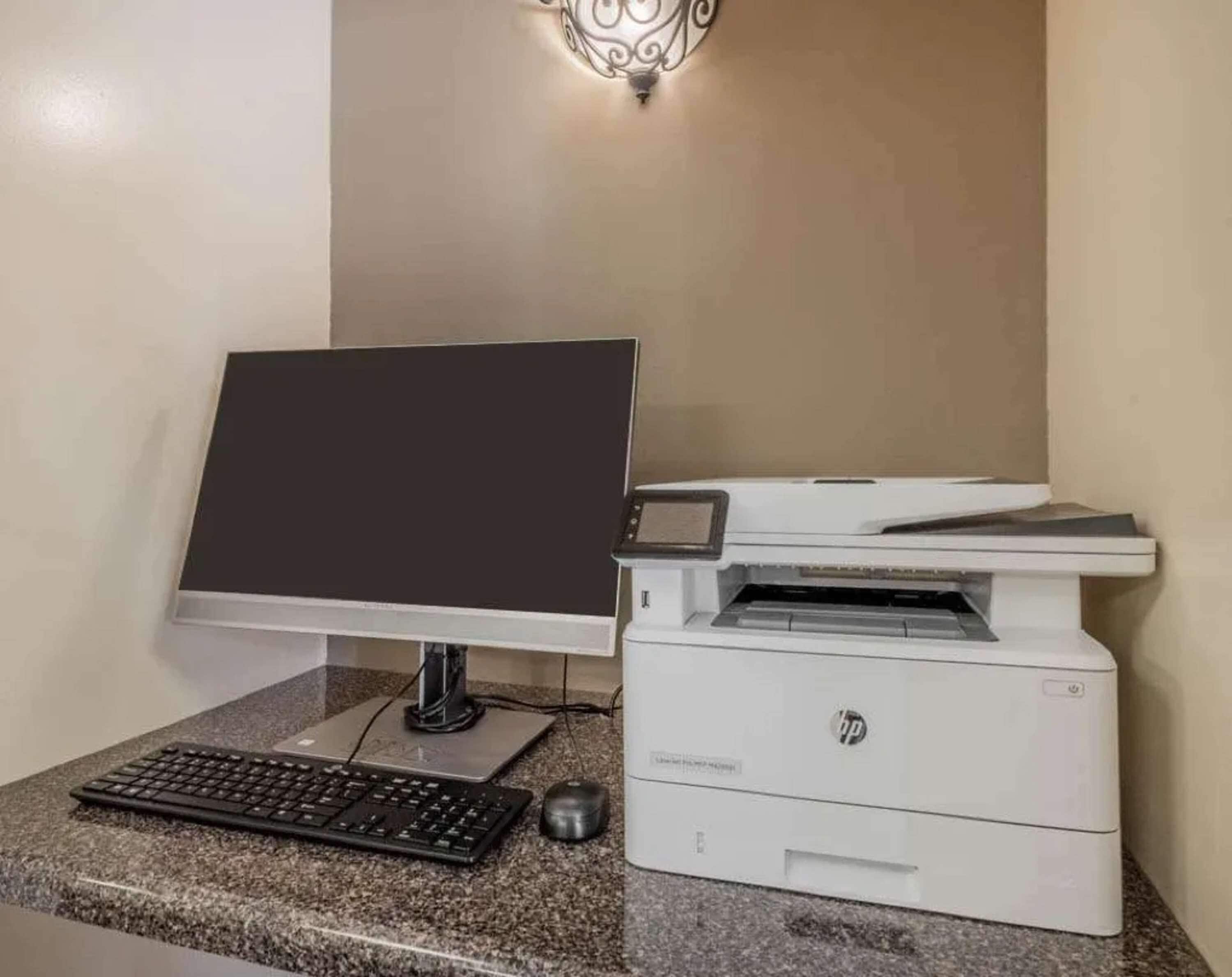 Una computadora de escritorio con monitor, teclado y ratón sobre una encimera de granito.
