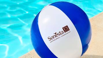 Una piscina al aire libre, sillones reclinables de piscina