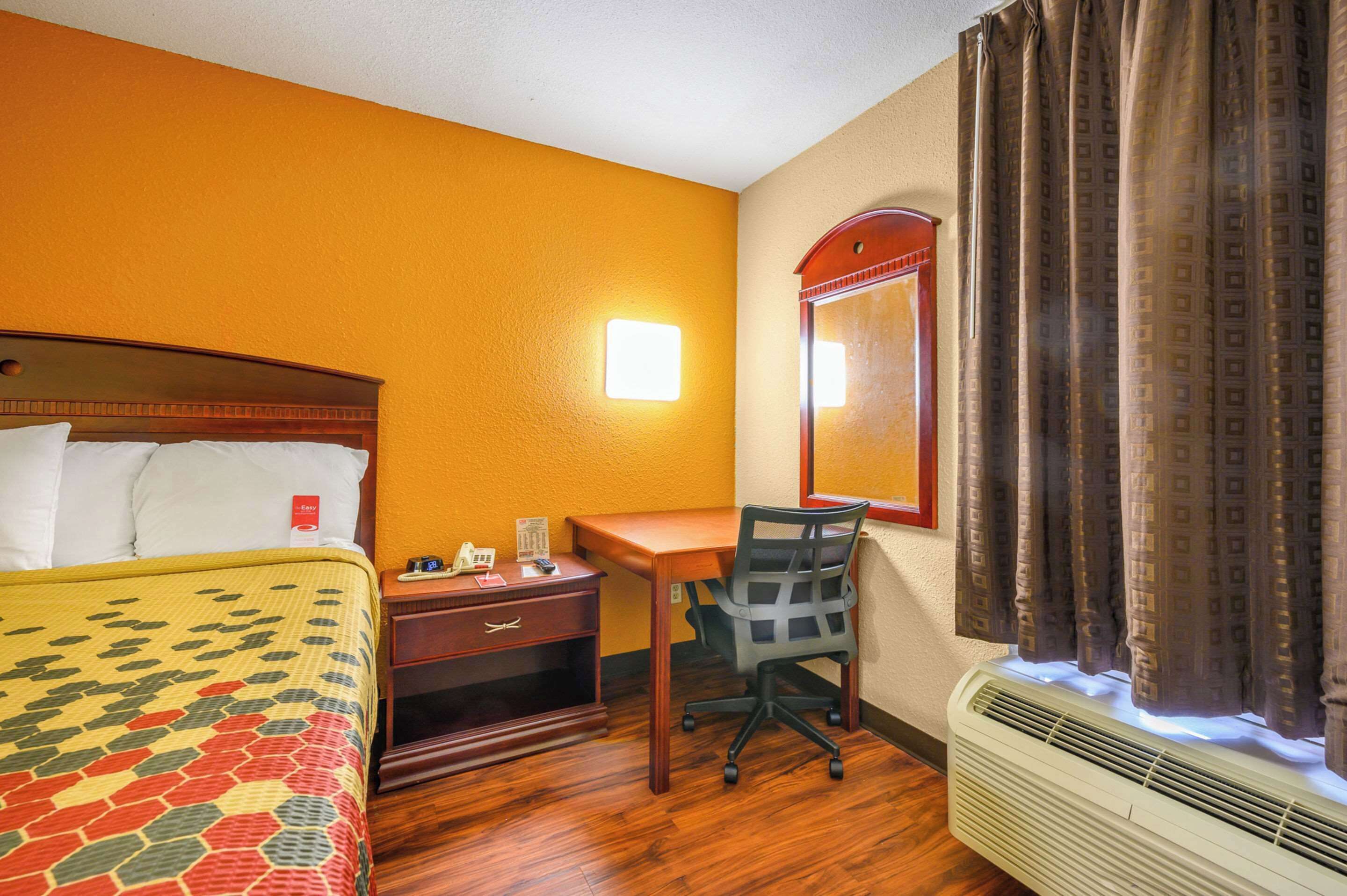 Ein Hotelzimmer mit Bett, Schreibtisch, Stuhl und Klimaanlage.