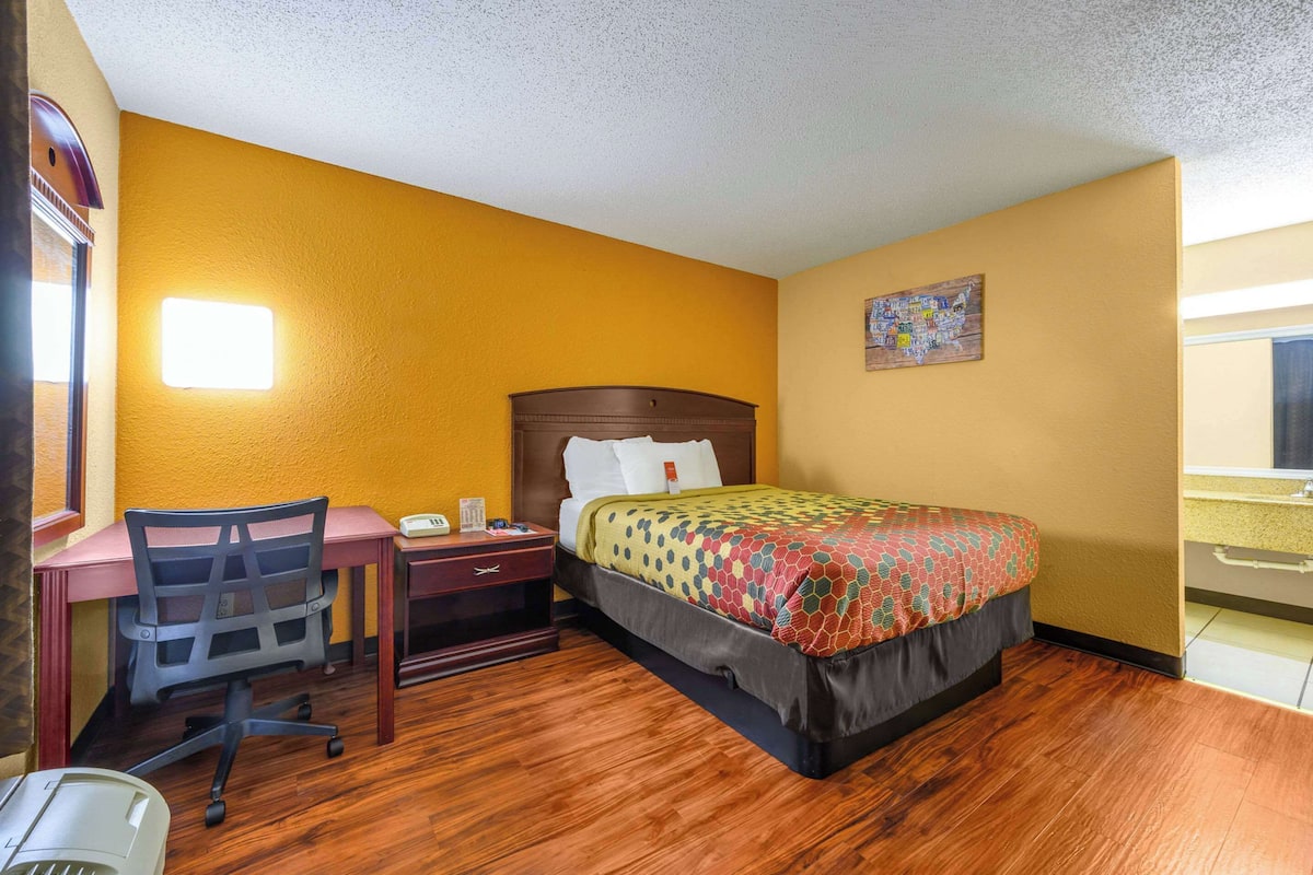 Una habitación de hotel con cama, escritorio, silla y una mesita.