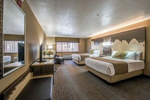 Relax in this stylish room with a large bed, a smaller bed, a desk, and a mirror.