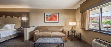 Ein Hotelzimmer mit Bett, Sofa, Couchtisch, Lampe, gerahmtem Bild, Fenster mit Blick und Heizung.