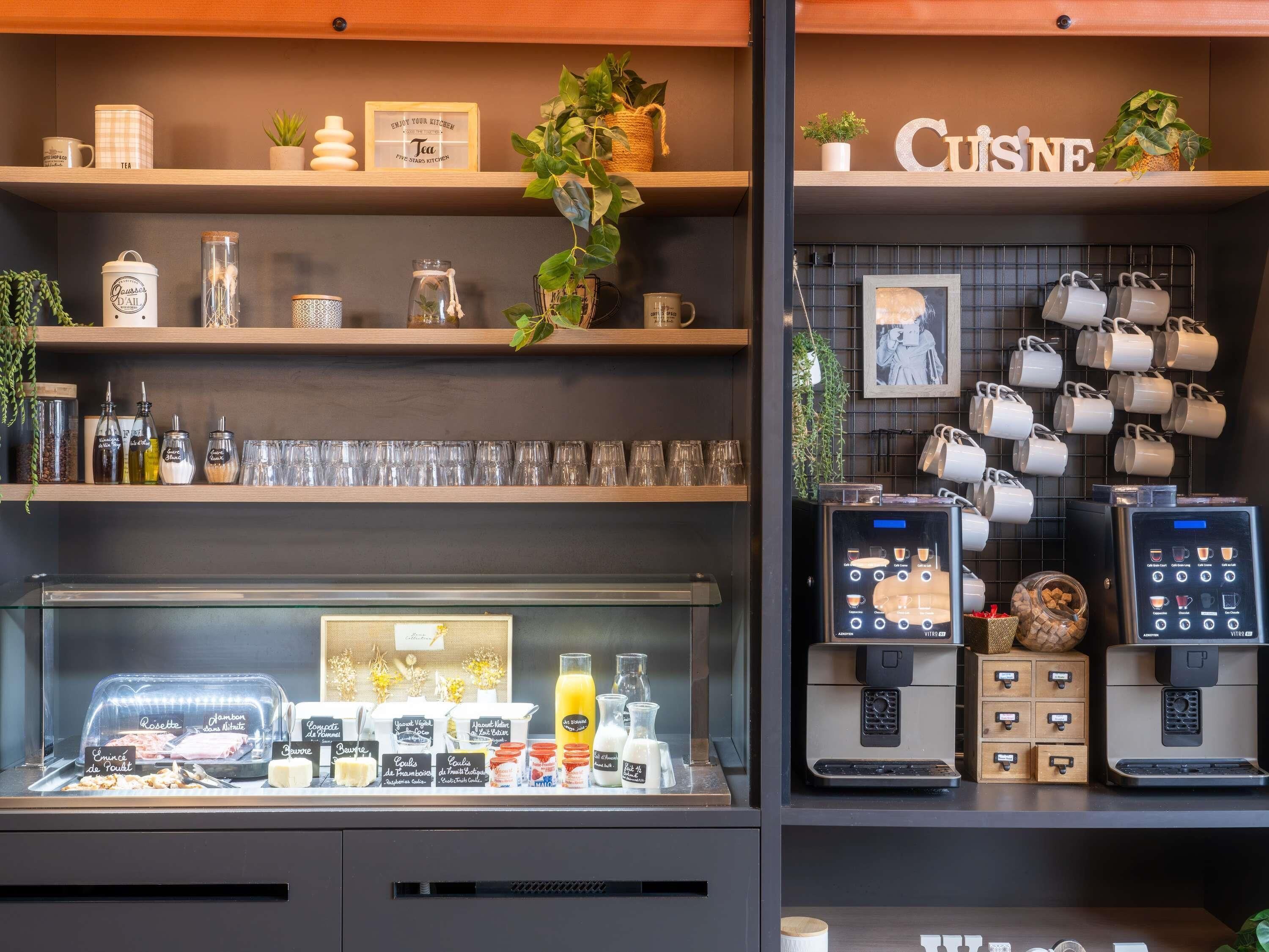 A coffee shop interior with shelves displaying tea and coffee mugs, a coffee machine, and various food items.