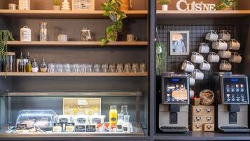 A coffee shop interior with shelves displaying tea and coffee mugs, a coffee machine, and various food items.