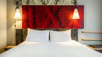 Een net opgemaakt bed met witte lakens, een abstract kunstwerk aan de muur en twee hanglampen.