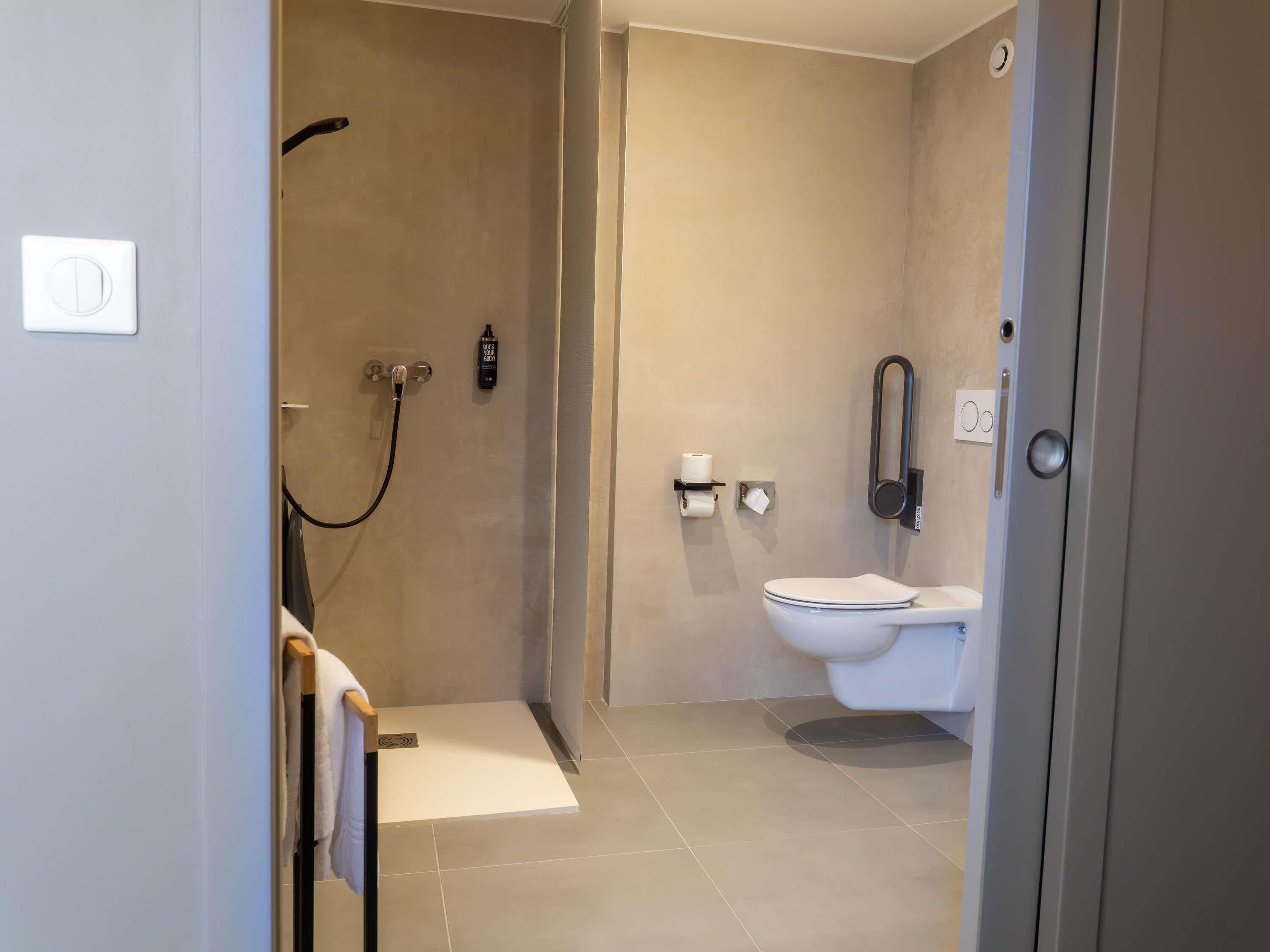 A modern bathroom with a shower, toilet, and towel rack.