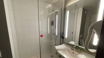 Een moderne badkamer met een douchecabine van glas, een witte wastafel en een grote spiegel.