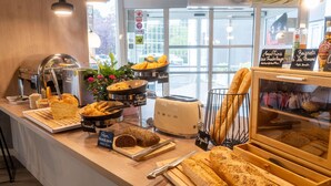 A bakery counter with various baked goods, a toaster, and a display case with bread. - ibis Compiègne (Compiègne)