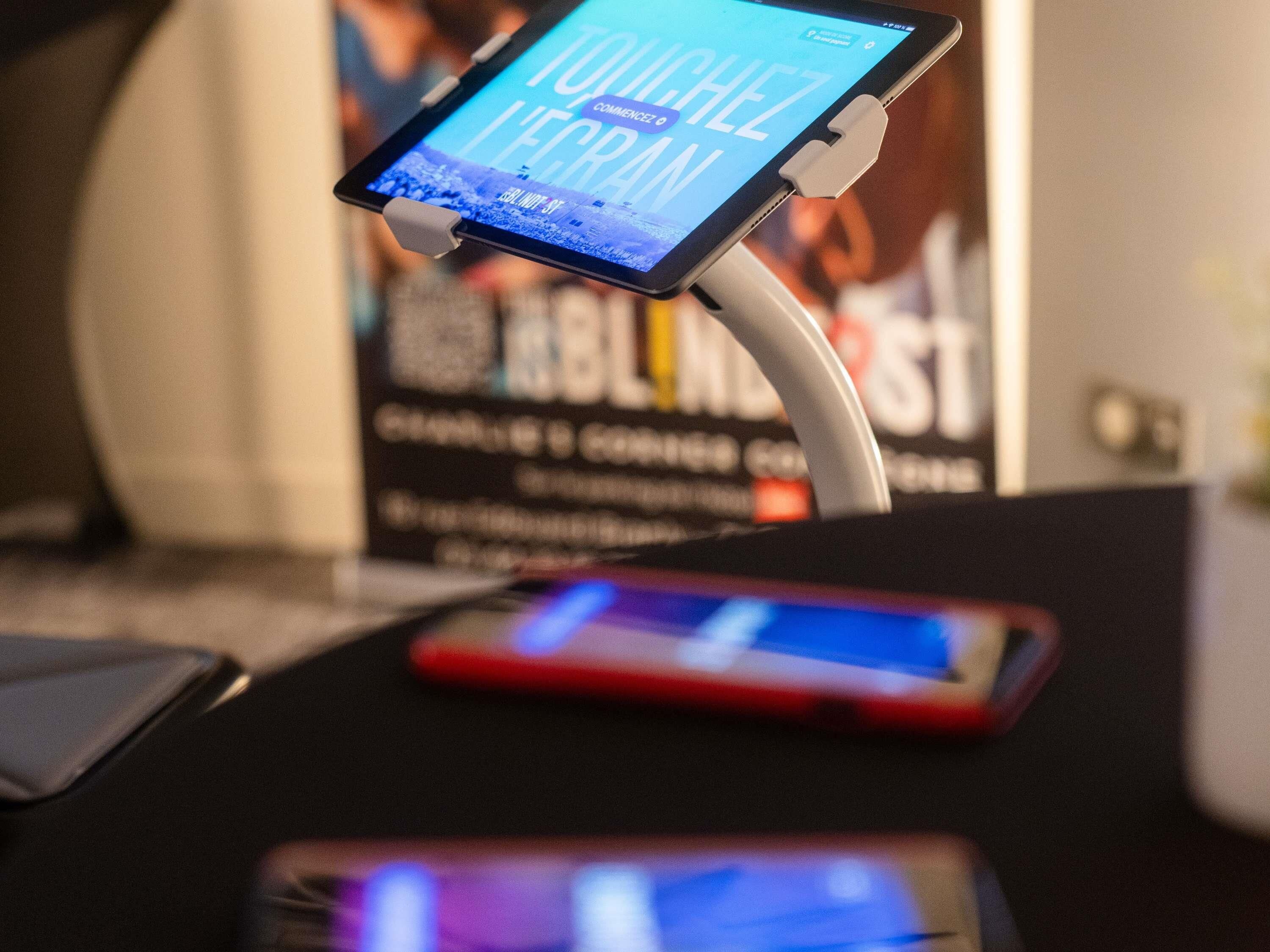 A tablet on a stand with a smartphone on a table, both displaying screens.