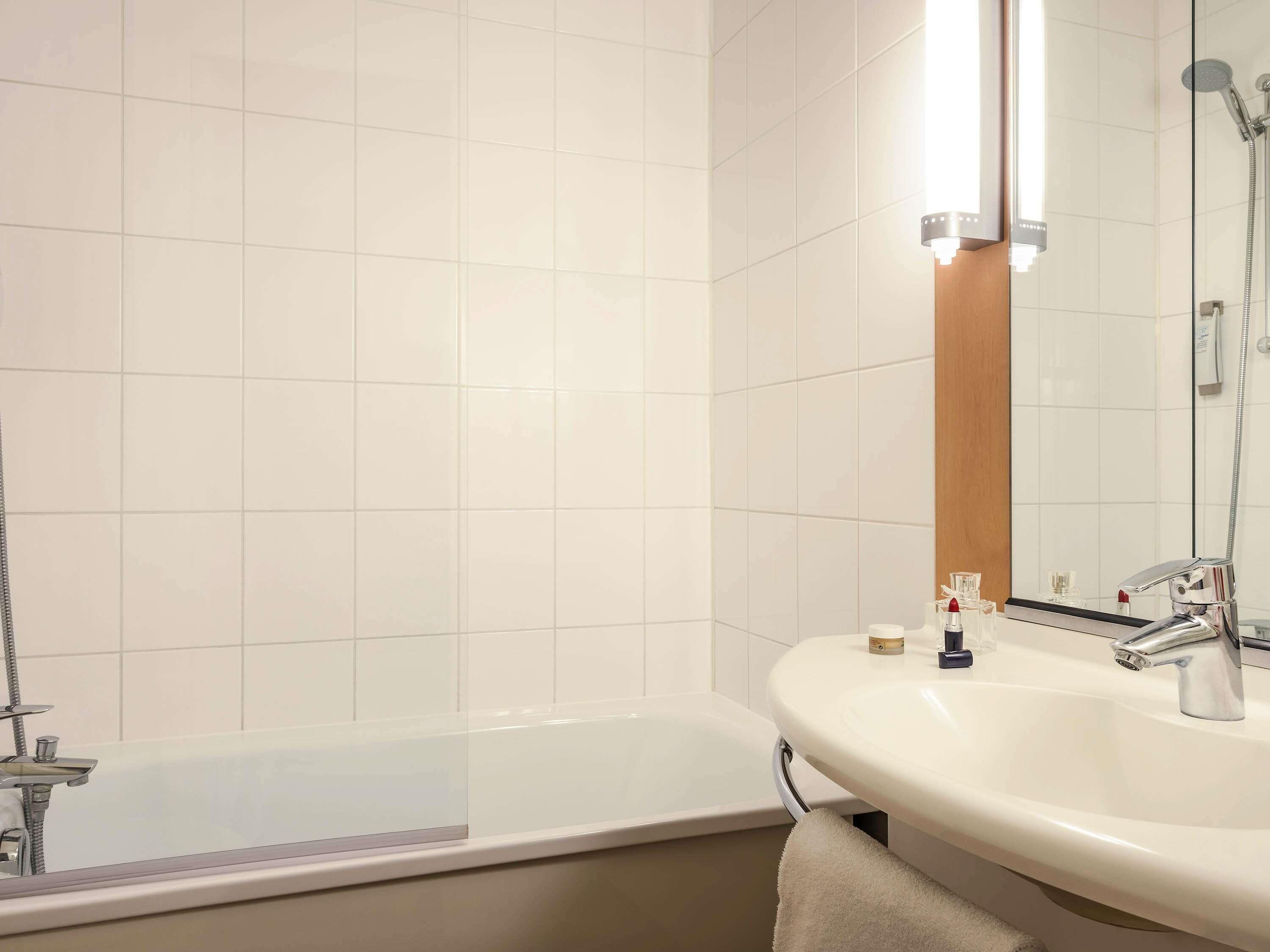 A bathroom with a bathtub, a sink, and a mirror.