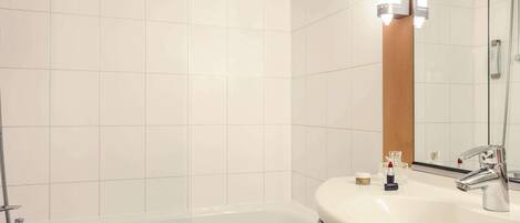 A bathroom with a bathtub, a sink, and a mirror.